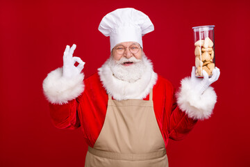 Photo of white grey hair bearded santa claus hold bake ginger bread cookies show okay sign wear chef headwear apron costume isolated bright shine color background