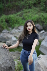 Stylish blonde girl wearing a black shirt with views of natural rocks, lake water and clear sky. female t-shirt models for mockups and templates.