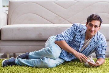 Young man playing with pet rabbit at home