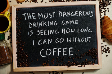 The most dangerous drinking game is seeing how long i can go without coffee. Words on blackboard flat lay.