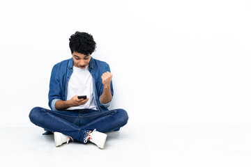 Venezuelan man sitting on the floor surprised and sending a message