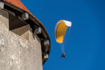 paragliding hang glider in the blue sky in bled castle tower