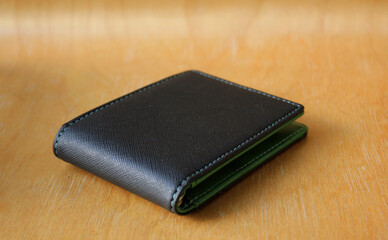 Black wallet isolated on wooden background . Closed wallet . 