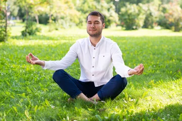  Young man meditates in lotus pose on green grass © adam121