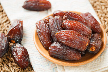 Date fruit in wood bowl on Wicker placemat, Dried date palm fruits top view