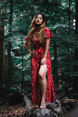 Fototapeta premium Beautiful Asian woman in red dress standing in a forest