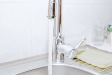 Faucet in the kitchen. Concept of using water in the kitchen. Water pouring from the tap in the kitchen. Water saving.