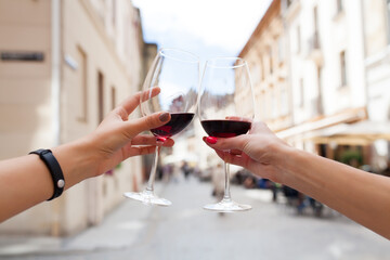hands close up of couple toasting glasses of wine, traveling in europe, summer vacation, drinking alcohol, point of view