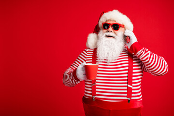 Fototapeta na wymiar Portrait of his he nice handsome cheerful cheery bearded fat overweight Santa wear costume drinking cacao eggnog talking on phone isolated bright vivid shine vibrant red color background