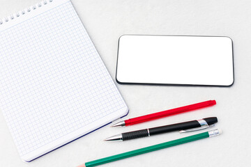 Notebook, pens, smart phone, closeup, top view, copy space