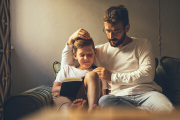 Father and son spend time together, reading a book during the afternoon rest