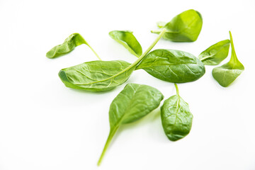Fototapeta premium Spinach on a light background. Concept of eating vegetables. Veganism and healthy eating. Spinach leaves lie on a white table.