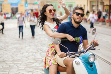 Naklejka premium young beautiful hipster couple riding on motorbike city street, summer europe vacation, traveling, romance, smiling, happy, having fun, sunglasses, stylish outfit, together in love, adventures, date