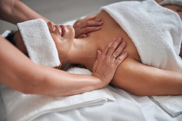 Fototapeta na wymiar Masseur hands massaging female shoulders in spa salon