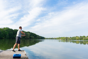 Naklejka premium Man fishing on the pier. Fishing on the river on a sunny day. Autumn predator fishing