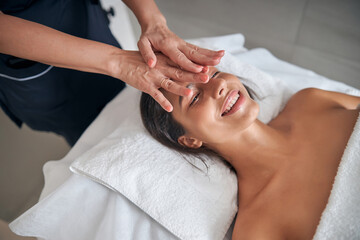 Obraz na płótnie Canvas Masseur hands massaging female face in spa salon