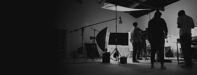 Behind the scene of photo shooting and production set up in the big studio. Professional crew team working and camera equipment in silhouette. such as light box, tripod, flashlight. and copy space.