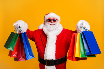 Portrait of his he nice attractive cheerful cheery fat Santa holding in hands carrying things buyings retail store boutique black Friday isolated bright vivid shine vibrant yellow color background