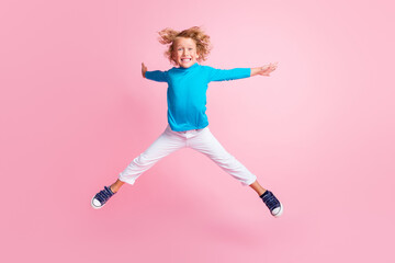Full length photo of small child jump legs hands star wear blue turtleneck pants sneakers isolated pastel pink color background