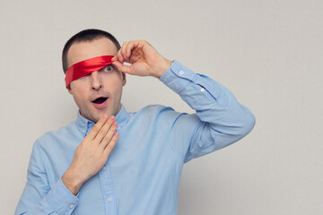 Excited and dazed man removes red blindfold, portrait, white background, copy space