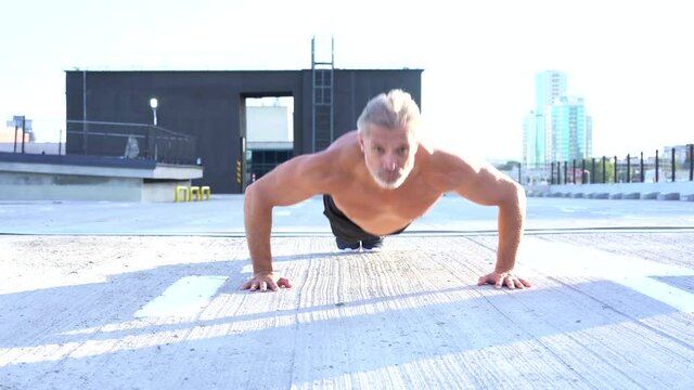 The Bearded Man Is Working Out In Outdoor Urban Environment. Push Ups.