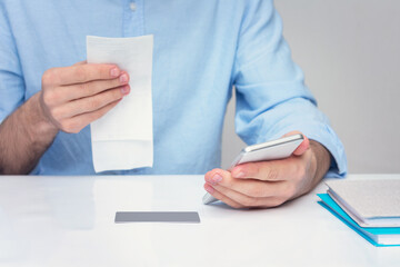 Husband paying bills via a phone, man's hands, cropped image, closeup
