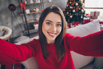 Photo of positive girl make selfie sit divan in house indoors with x-mas christmas advent decoration