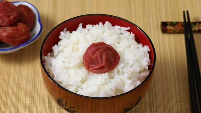 Bowl with rice and traditional Japanese umeboshi close up