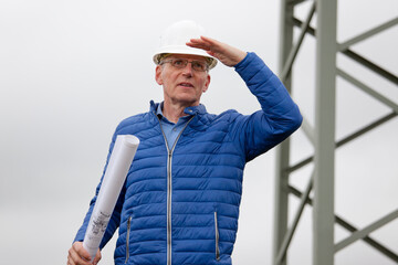 Architect or engineer with hard hat and blueprint in his hand looking out  for something
