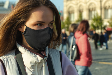 The young woman in the black mask walking around the city caring herself from a virus. 