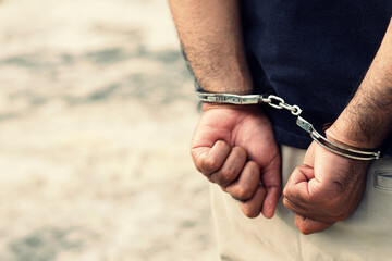 Arrest the offender. Prison male criminal standing in handcuffs with hands behind back. 