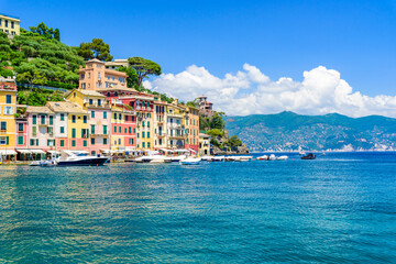 Fototapeta na wymiar Portofino, Italy - Harbor town with colorful houses and yacht in little bay. Liguria, Genoa province, Italy. Italian fishing village with beautiful sea coast landscape in summer season.