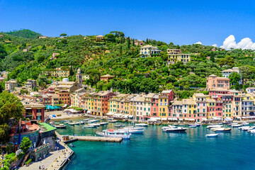 Fototapeta na wymiar Portofino, Italy - Harbor town with colorful houses and yacht in little bay. Liguria, Genoa province, Italy. Italian fishing village with beautiful sea coast landscape in summer season.