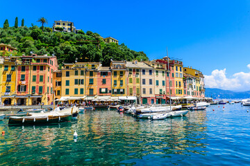 Obraz premium Portofino, Italy - Harbor town with colorful houses and yacht in little bay. Liguria, Genoa province, Italy. Italian fishing village with beautiful sea coast landscape in summer season.