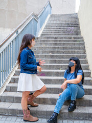 Two caucasian young women taking in the street with face masks during covid. Friendship, millennial and coronavirus concept.