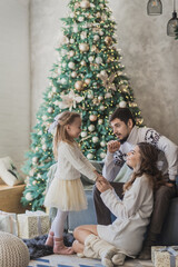 Fototapeta na wymiar Happy family in christmas decorations. Mother father and little daughter in day time cozy christmas atmosphere
