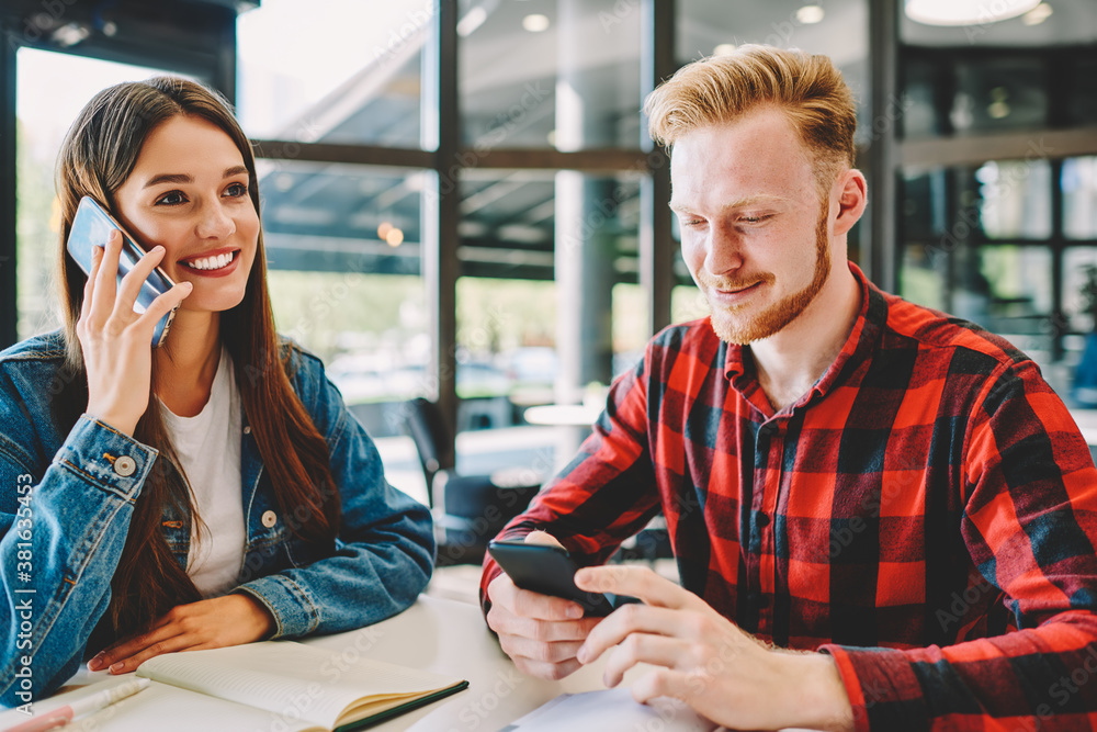 Aufkleber cheerful female hipster student using cellular device for making positive mobile conversation during