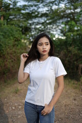 a stylish young woman wearing a white T-shirt against the backdrop of a forest view. black t-shirt models for mockups and templates.