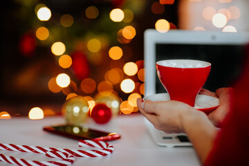 Woman's hands holding cup of marshmallows against Christmas background. Copy space.