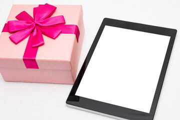 Pink gift and tablet, white background, closeup, copy space, top view