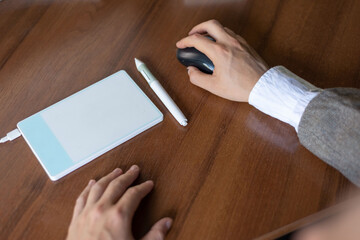 businessman sitting at the table, signs in a graphics tablet with a stylus. Close-up. Business. Electronic signature using a pen tablet