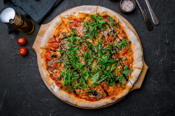 Italian meat pizza with aragula on black concrete table top view