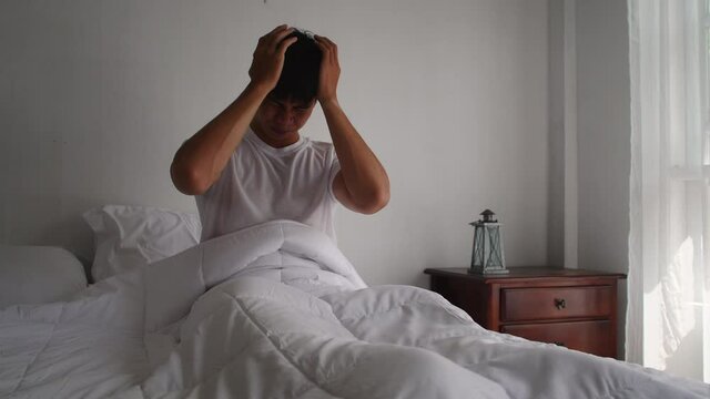 A young Asian man wake up with a headache and a feverish fever.