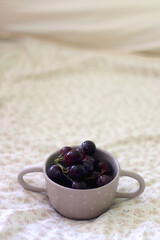 Bowl of grapes on a bed. Selective focus.