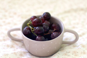 Bowl of grapes on a bed. Selective focus.