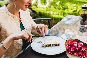 young stylish woman sitting in cafe, eating tasty pie, enjoying healthy food, tulips, happy birthday party, city street, boho outfit, europe vacation, fashion, romantic dinner, hands, close up, detail