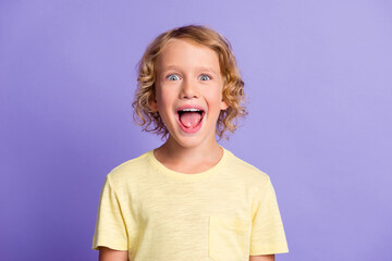Portrait of astonished little boy look in camera yell loudly wear yellow clothes isolated over purple color background