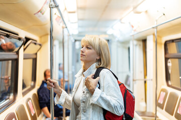 Portrait of beautiful adult woman with backpack stands in the subway and looks ahead