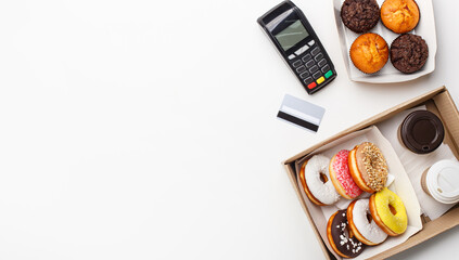 Bill payment and ordering sweets. Contactless terminal, credit card, cupcakes and muffins, coffee cups and donuts with glaze