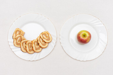 Red apple and sponge roll cut into pieces on a white plates, top view, copy space